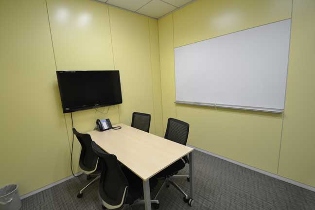 明るい黄色の壁が印象的なモニターを常設した会議室