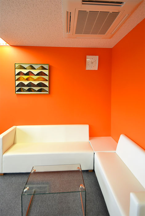 オレンジの壁と白いソファが印象的なリフレッシュルーム