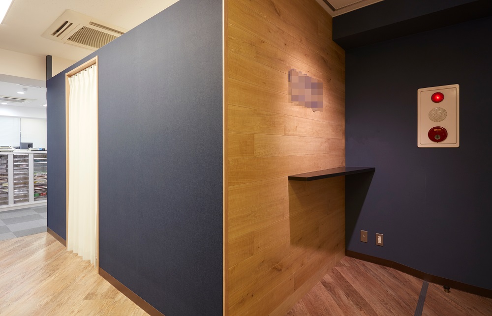 ネイビーの壁クロスと木目が印象的なオフィスの小スペース