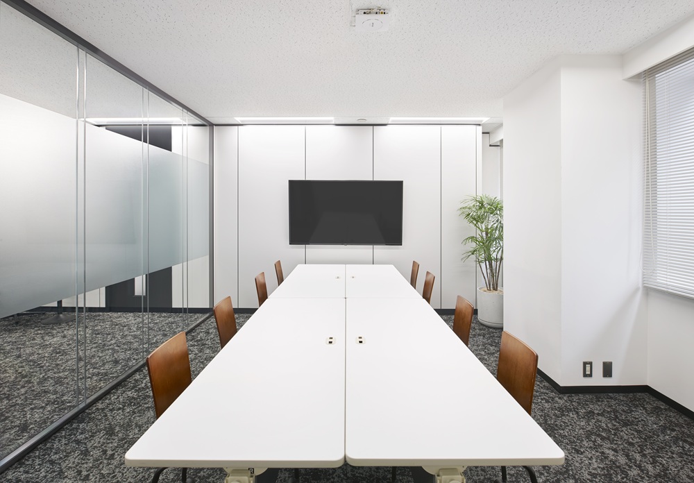 ガラスパーテーションで仕切られた明るい社内会議室
