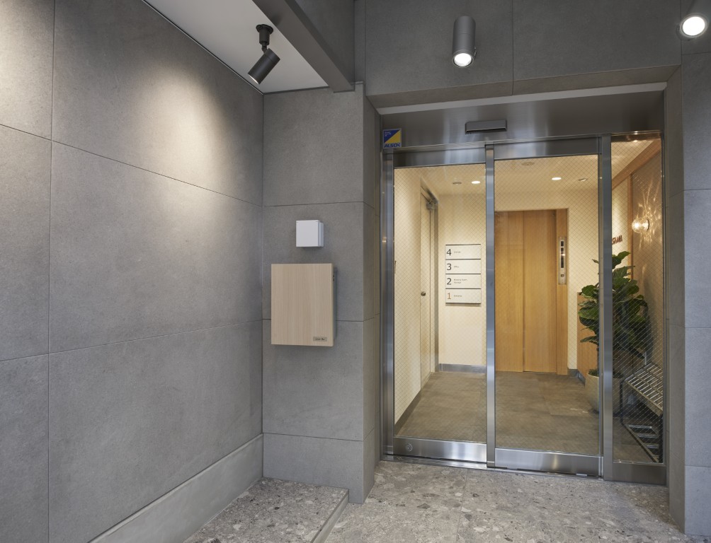 周りの景色に馴染む、明るい自社ビルの外壁