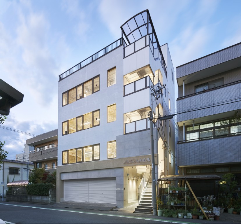 周りの景色に馴染む、明るい自社ビルの外壁